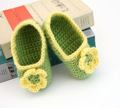 a pair of crocheted slippers sitting on top of a stack of books