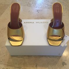 New, In Original Box, Amina Muaddi Lupita Slipper Sandals In Gold In Size 40 - Rare Color And Sold Out Worldwide! - Leather Upper And Sole - Made In Italy - Square Toe - Original Box And Dustbag Included ** Slight/Faint Mark On The Bottom Of One Sole From Trying On The Shoe On Tile At Home - As Pictured On Last Photo. Luxury Gold Mules With Block Heel, Gold Square Toe Sandals For Evening, Luxury Gold Mules With Padded Heel, Chic Gold Square Toe Sandals, Gold Square Toe Evening Sandals, Designer Gold Sandals With Square Toe, Gold Mules With Padded Block Heel, Designer Gold Sandals With Wrapped Heel, Luxury Gold Mules For Party