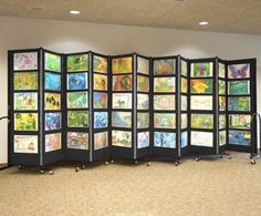 a room divider with pictures on it in front of a wall and carpeted floor