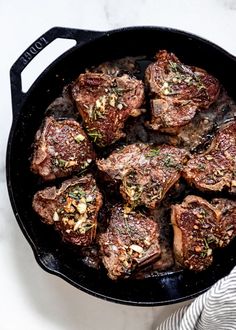 steaks in a cast iron skillet on a marble counter