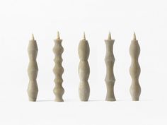 four candles are lined up in the same row on a white surface, one is turned upside down