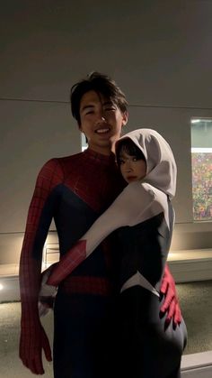 a man in a spiderman costume holding a doll with his arm around the woman's shoulders