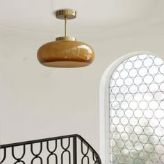 a light fixture hanging from the ceiling next to a window with a circular design on it