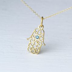 Tiny Hamsa pendant in solid gold with a tiny natural blue diamond in the centre.  - length: 0.6 inches / 1.5 cm   - width 0.4 inches / 1.1 cm Available in 9k, 14k and 18k yellow, white and rose gold.  The pendant is available with a solid gold chain or without a chain (pendant only). It will be a 9k solid gold chain for the 9k pendant, a 14k solid gold chain for the 14k pendant and a 18k solid gold chain for the 18k pendant.   Beautiful filigree pendant, Fatima hand with tiny evil eye. Protection Charm, also available without the diamond. For other colors please contact me. Perfect gift for Valentine, Mother's Day or any other special occasion. Minimalist Gold Jewelry With Blue Topaz, Blue 14k Gold Necklace With Charms, Gold Birthstone Necklace With Blue Topaz For Gifts, Gold Blue Topaz Birthstone Necklace As Gift, Gold Blue Topaz Birthstone Necklace For Gift, Gift Gold Necklace With Blue Topaz, Spiritual Yellow Gold Sterling Silver Birthstone Necklace, Blue Recycled Gold Jewelry For Anniversary, Yellow Gold Blue Topaz Jewelry Gift