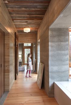 a woman walking down a hallway next to a wooden door and window in a house