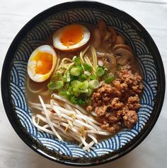 a bowl filled with noodles, meat and an egg on top of it next to other foods