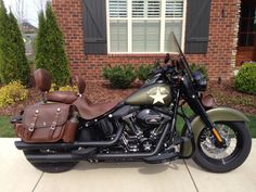 a green motorcycle parked in front of a house with a star on the back seat