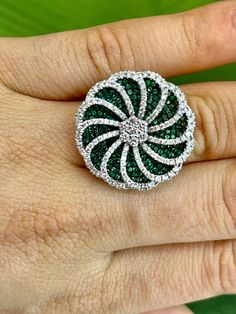 Fidget ring Emerald & Diamond Flower-Shaped Spinning Ring 1.19 carat natural Emerald 1.05 carat diamond pave setting 18k white gold Fresh, fun and a little bit flirty, this emerald and diamond flower-shaped fashion ring is truly a delight! Crafted in 18K white gold, this ring features a green emerald invisible paved base topped with white diamond ribbons creating a swirling flower shape. This ring is a lovely gift option for the May birthday girl! Available in all sizes, send us yours! Ring Desc Round Emerald Ring With Pave Diamond Setting, Diamond Ribbon, Spinning Ring, May Birthday, Spinning Rings, Fidget Rings, Ring Emerald, Pave Setting, Diamond Flower