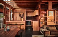 a kitchen and living room with wood paneling on the walls, wooden furniture, and open shelving