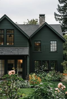 a large green house with lots of windows and flowers in front of the house is surrounded by greenery