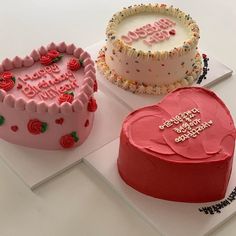 three heart shaped cakes sitting on top of each other in front of a white table