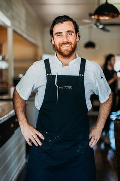 a man standing in a kitchen with his hands on his hips and smiling at the camera