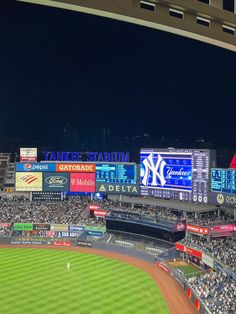 a baseball stadium filled with lots of people watching the game at night and lit up by bright lights