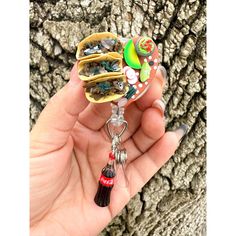 a hand holding a taco keychain in front of a tree