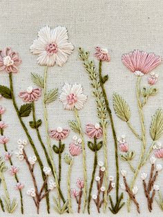 some pink flowers and green stems on a white cloth with bead work in the middle