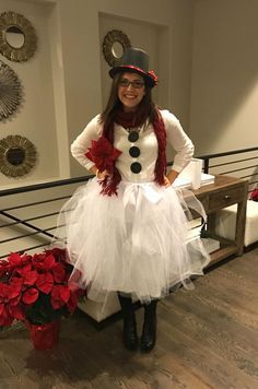 a woman in a snowman costume standing next to a bench with poinsettis