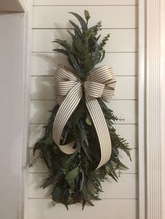 a wreath hanging on the side of a white door with a ribbon tied around it