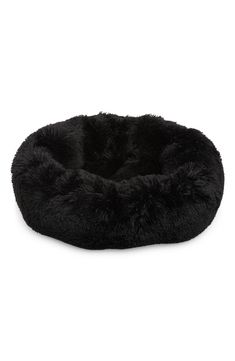 a black dog bed with fluffy fur on the top and bottom, in front of a white background