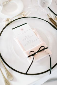 a place setting with white and black plates, silverware and napkins on it