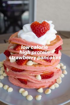 a stack of pancakes with strawberries and whipped cream on top, sitting on a plate