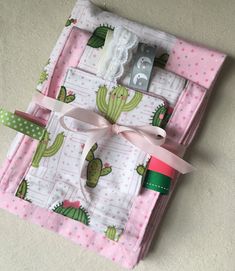 a pink and green cactus themed baby blanket with matching crochet hooks, pacifier holder, and sewing needle case