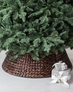 a christmas tree in a wicker basket with a white bow