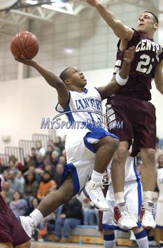 two men are playing basketball while people watch from the bleachers in the stands