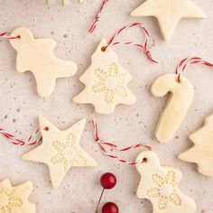 christmas cookies decorated with icing and decorations on a white countertop next to cherries