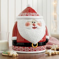 a santa clause cookie jar sitting on top of a table next to cookies and milk