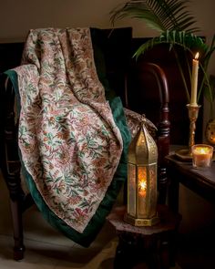 a blanket draped over a chair next to a candle and potted plant on a table