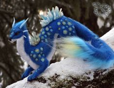 a blue and white dragon figurine sitting on top of a snow covered rock