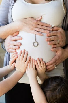 a group of people holding their hands on top of a pregnant woman's stomach