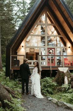 a bride and groom standing in front of a cabin