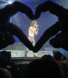 a man standing on top of a stage with his hands in the shape of a heart