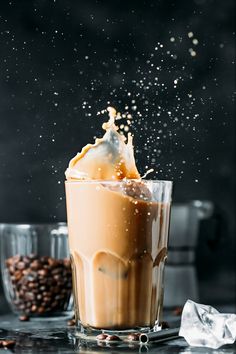 a glass filled with liquid next to some coffee beans