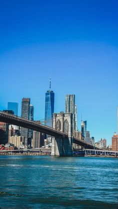 the skyline of new york city is seen from across the water in front of a bridge