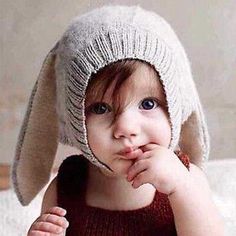 a small child wearing a knitted bunny hat