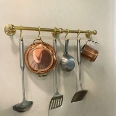 a rack with pots and pans hanging from it's hooks on the wall