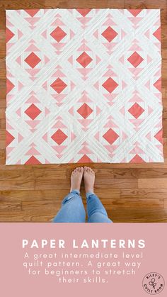 a person standing on top of a wooden floor next to a pink and white quilt