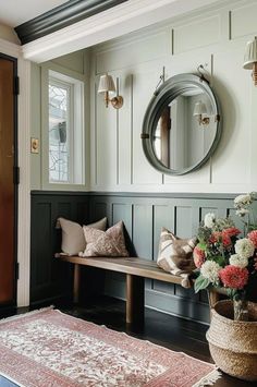 a wooden bench sitting in front of a mirror on the wall next to a vase with flowers