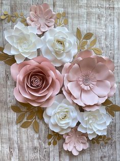 large paper flowers are arranged on a wooden surface with gold leaves and pink ones in the center