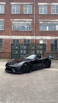 a black sports car parked in front of a brick building