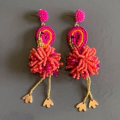 two pairs of pink and orange beaded earrings with dangling hooks on grey surface,