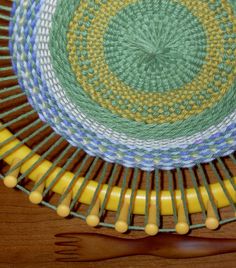 a green and yellow plate with wooden utensils in it on a wood table