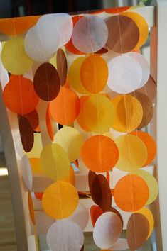 an orange and white chair is decorated with paper circles hanging from it's back