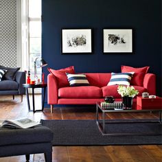 a living room with blue walls and red couches on the floor, two pictures hanging on the wall