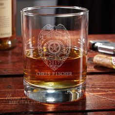 a glass filled with whiskey sitting on top of a wooden table next to a bottle