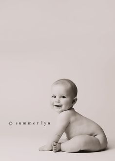 black and white photograph of a baby sitting on the floor with his hands in his pockets