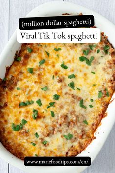 a casserole dish with cheese, meat and herbs in it on a white wooden table