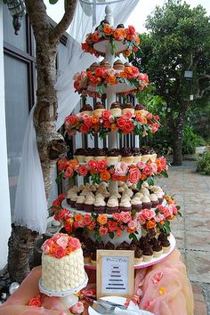 a wedding cake with cupcakes and flowers on the top is surrounded by other desserts